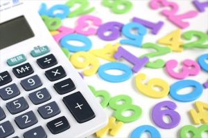 計算機と金額をイメージさせるたくさんの数字が撒かれた様子